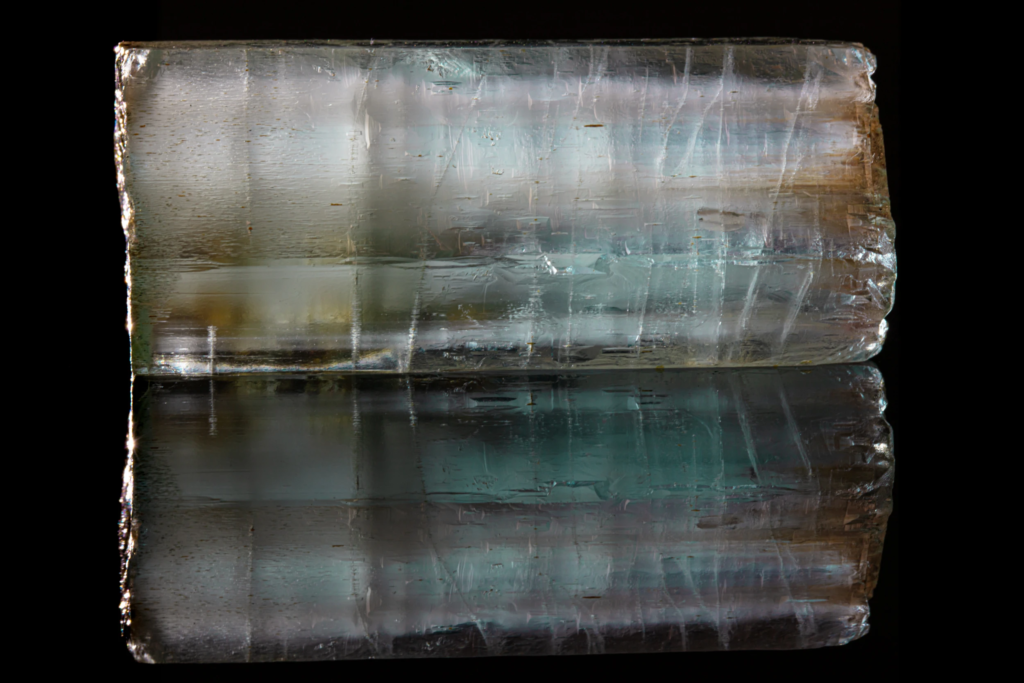 Horizontal blue aquamarine crystal prism from Namibia with mirror reflection.