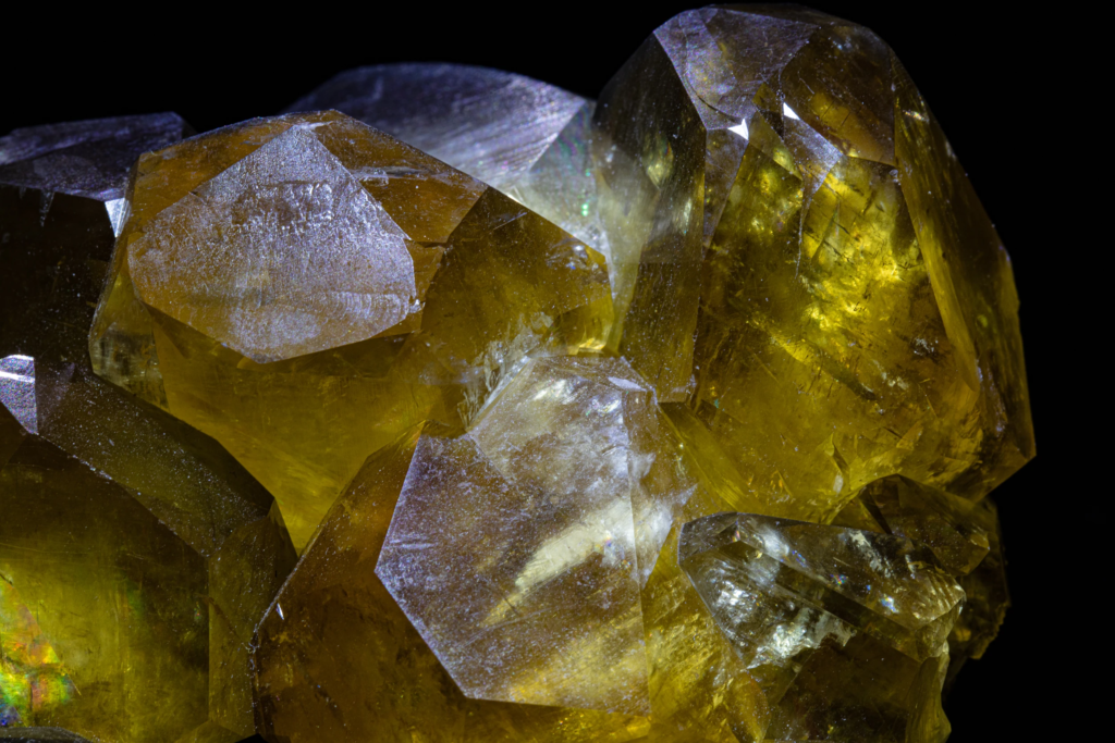 Backlit golden yellow calcite crystals from China glowing against black background.