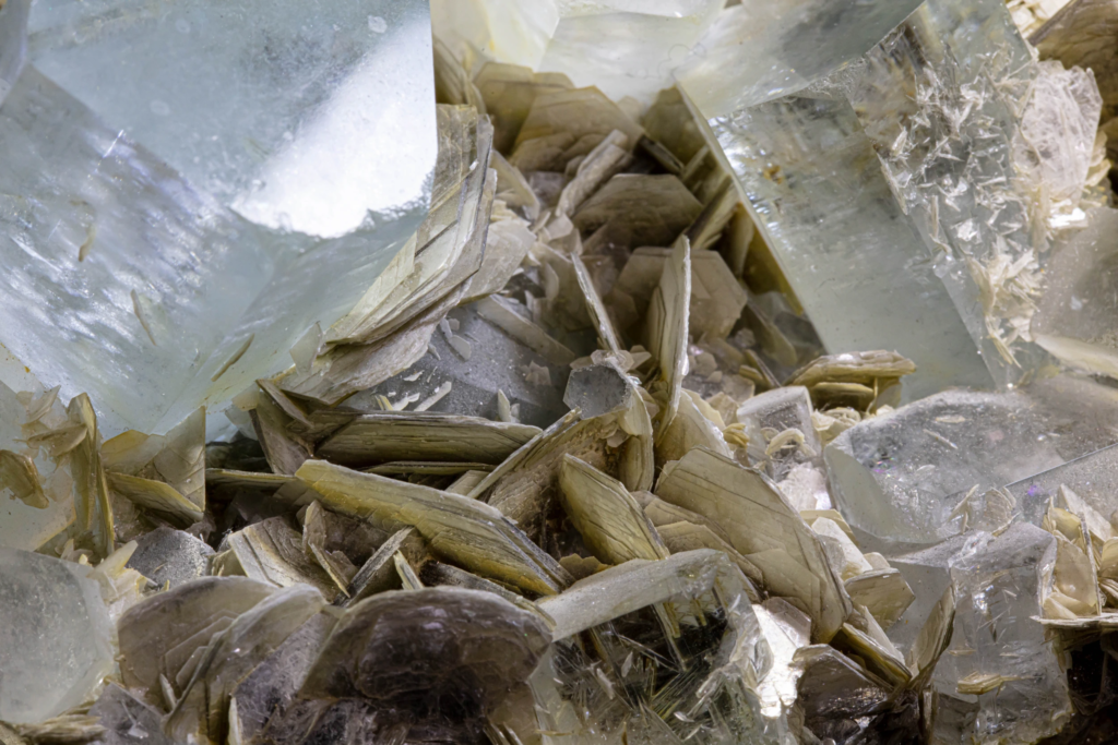 Hexagonal pale blue aquamarine prisms growing from silvery muscovite rosettes, Pakistan.