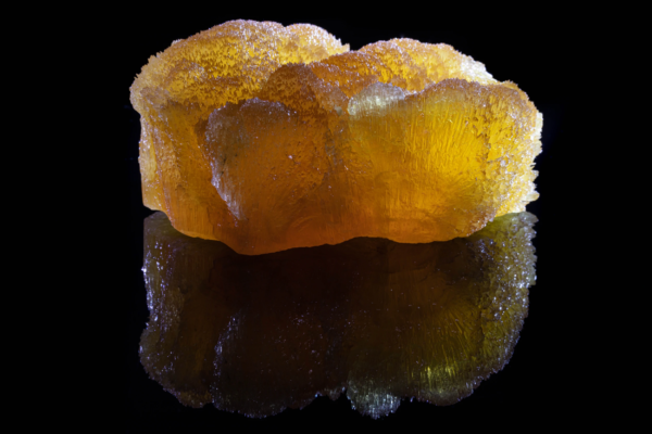 Honey yellow radiating calcite aggregate from France with a mirror reflection.