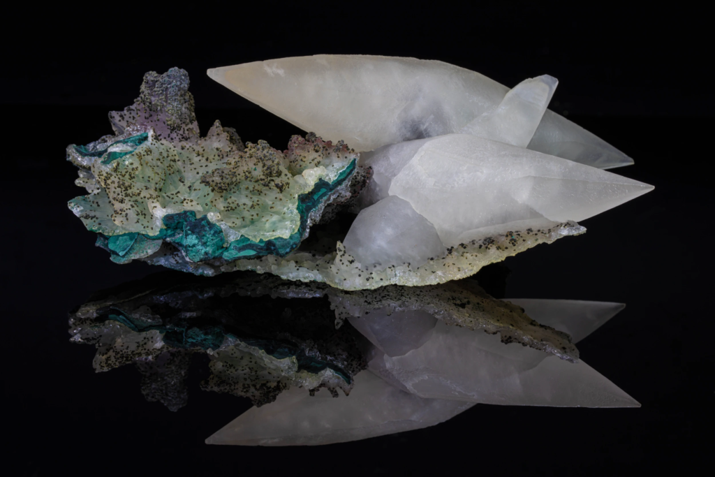 Translucent white calcite crystals on green matrix from Brazil with reflection.