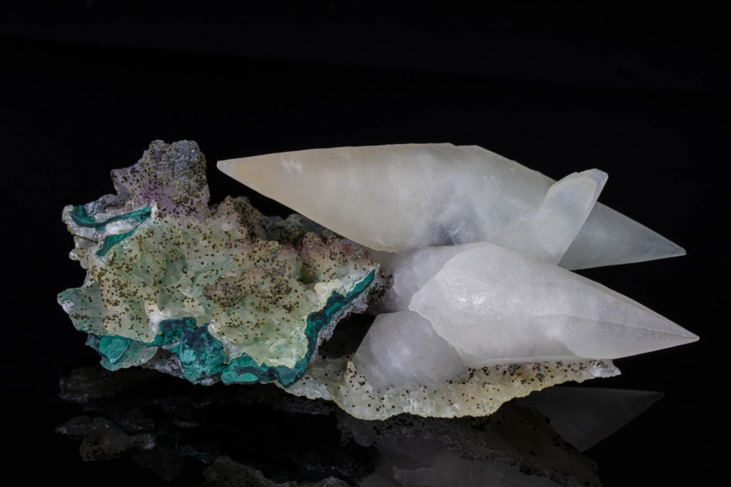 Translucent white calcite crystals on green matrix from Brazil against black.