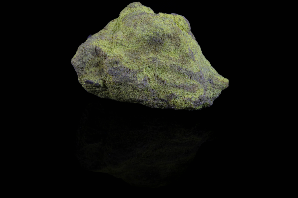 Bright yellow carnotite crust on matrix from the USA with reflection.