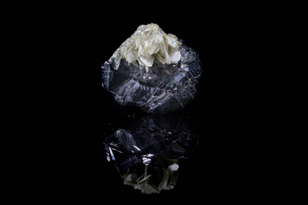 Pale green muscovite on black cassiterite crystal from China with reflection.