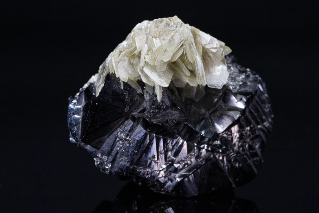 Close-up of tabular muscovite blades on a black cassiterite matrix.