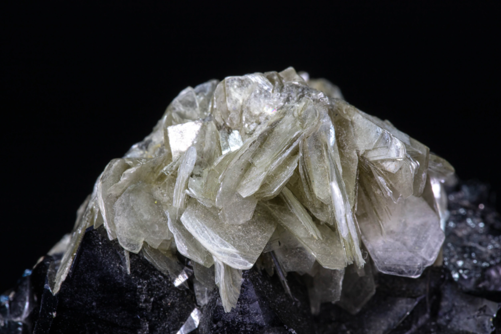 Macro photograph of pearly tabular muscovite crystal packages on cassiterite.