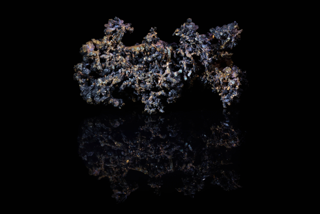 Dendritic native copper cluster with dark cuprite crystals and mirror reflection.