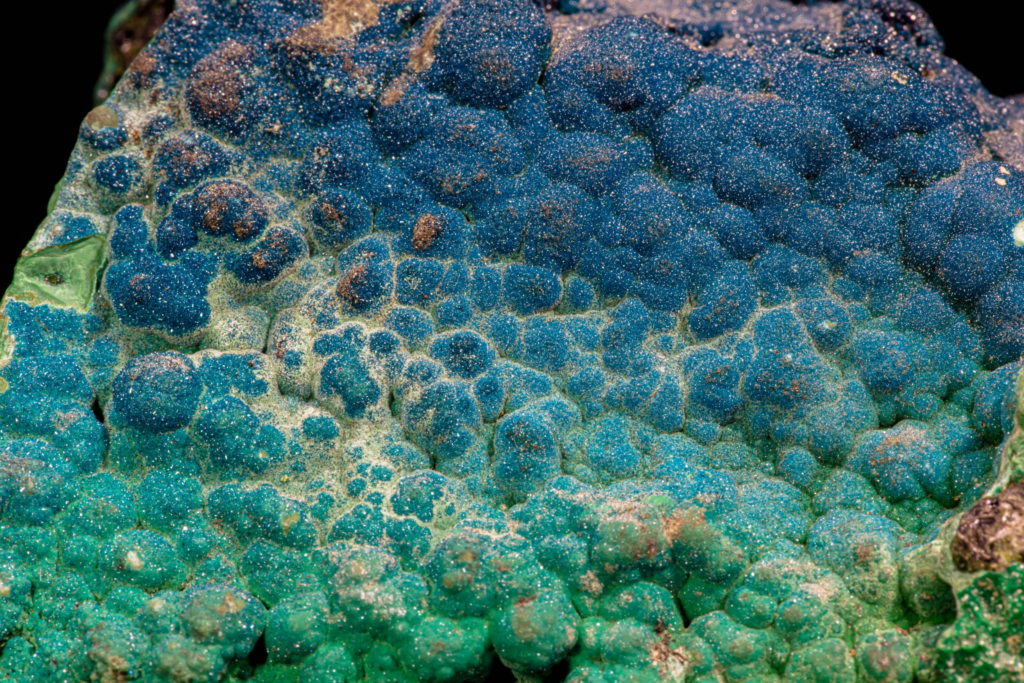 Deep blue sparkling cornetite mineral layer from Congo against black.