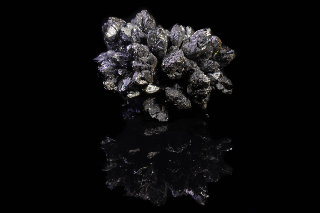 Dark lustrous descloizite crystal cluster displaying a vertical mirror reflection.