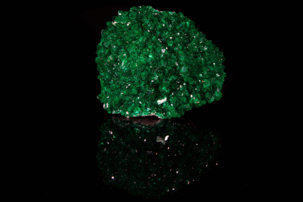 Emerald green dioptase crystal cluster displaying full vertical mirror reflection