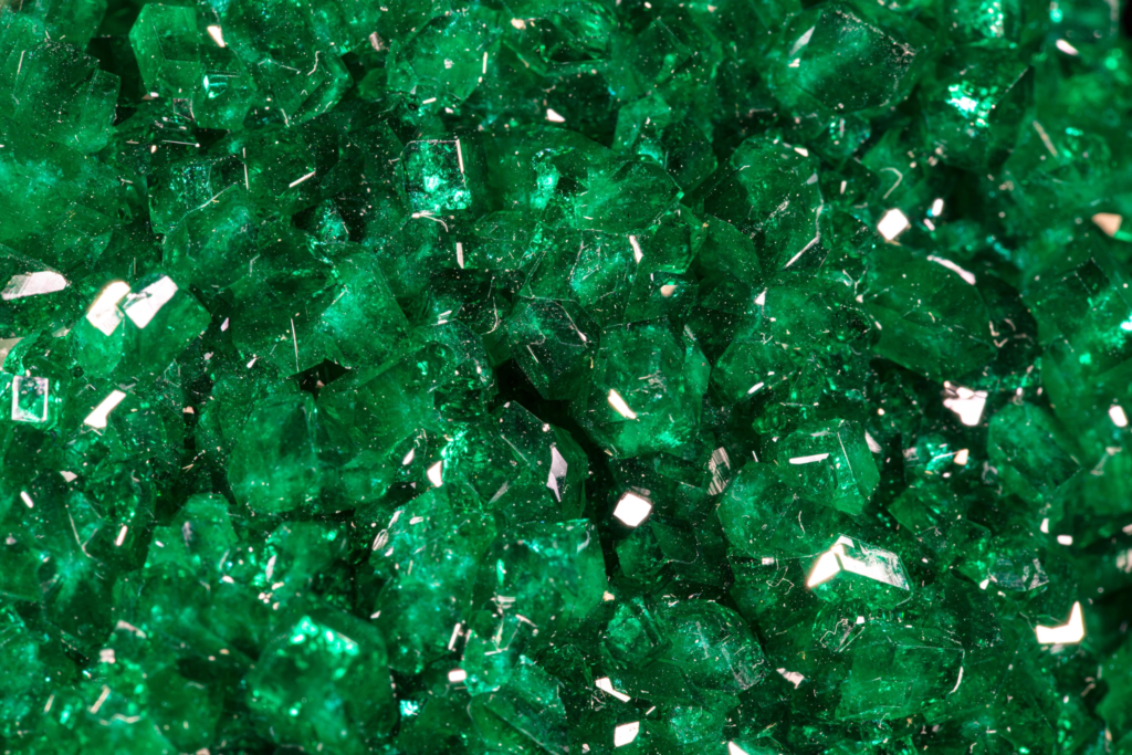 Macro photograph detailing sharp translucent faces of emerald green dioptase