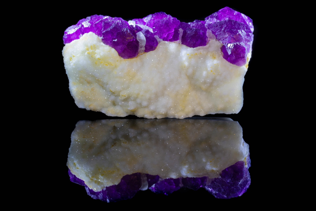 Rear view of white botryoidal matrix under purple fluorite with reflection.
