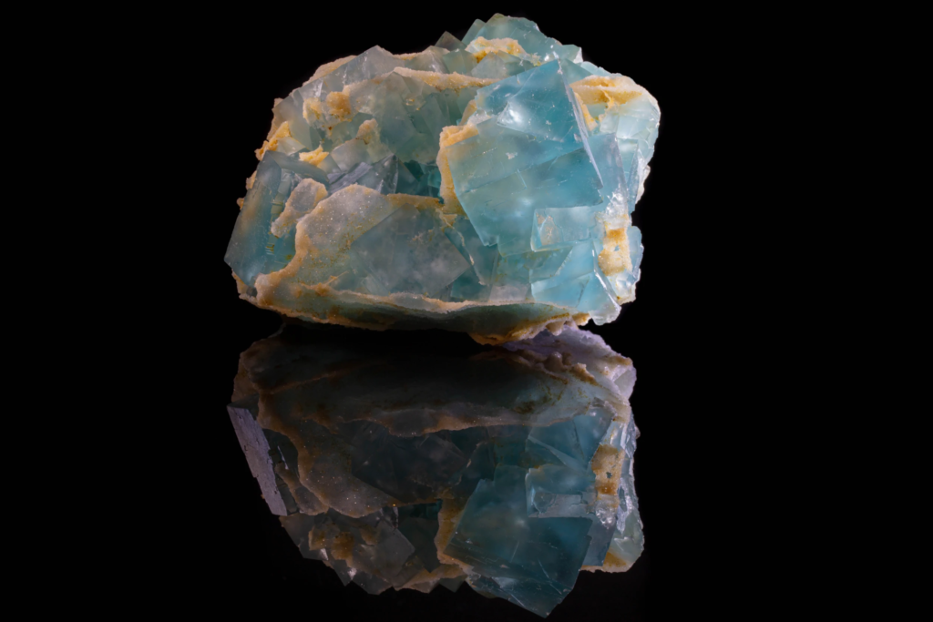 Light blue cubic fluorite cluster on matrix with mirror reflection.