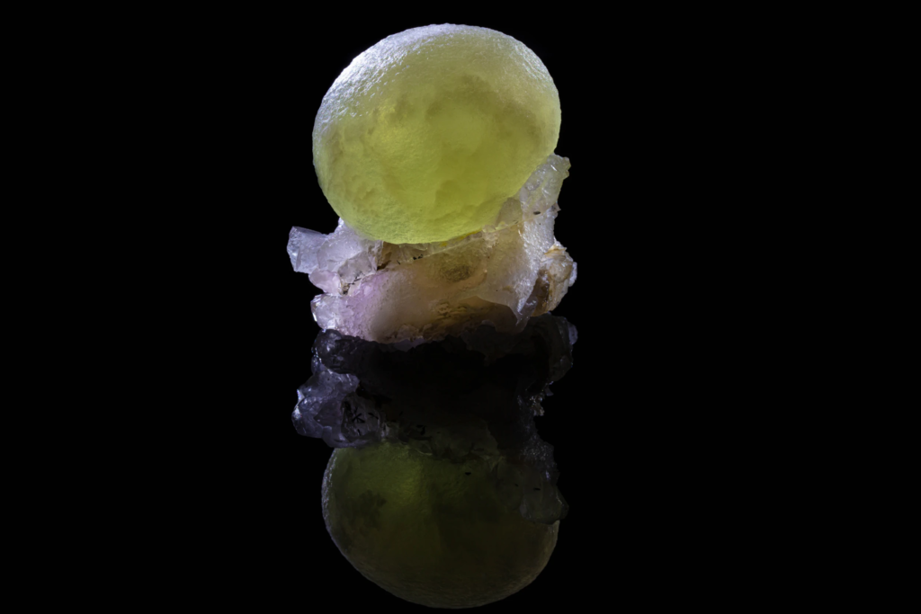 Yellow spherical fluorite crystal on matrix with a mirror reflection.