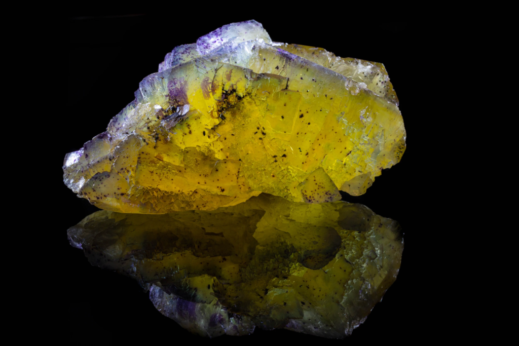 Yellow cubic fluorite cluster with purple zoning and mirror reflection.