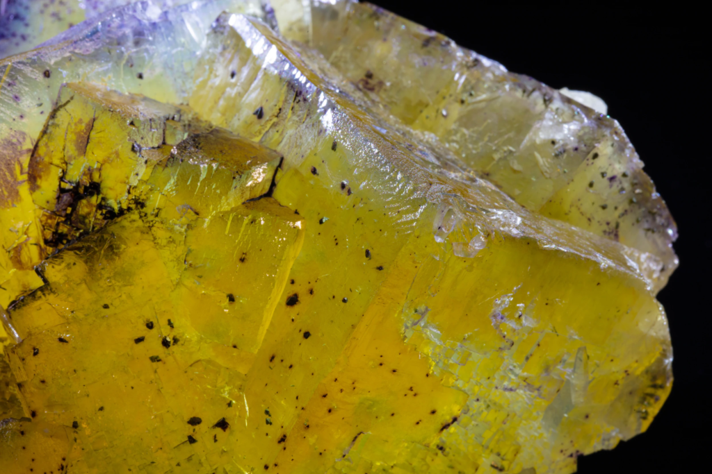 Macro photograph detailing cubic growth steps on translucent yellow fluorite.