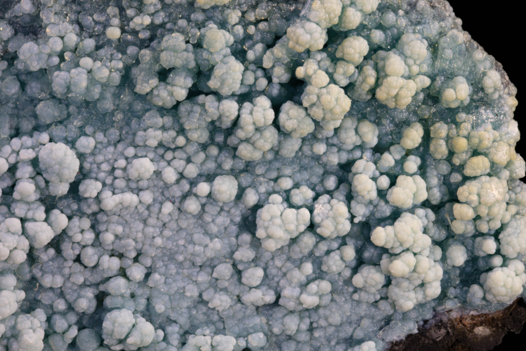 Close macro photograph detailing translucent light blue botryoidal gibbsite spheres.