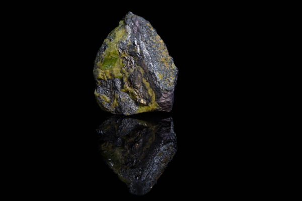 Black metallic ilmenite with green titanite displaying a vertical reflection.