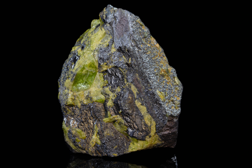 Upright black ilmenite specimen with translucent green titanite without reflection.