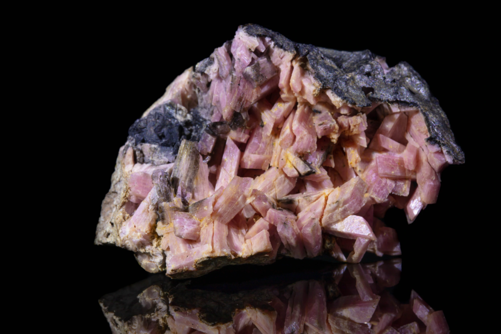 Close front view of a translucent pink inesite crystal group.