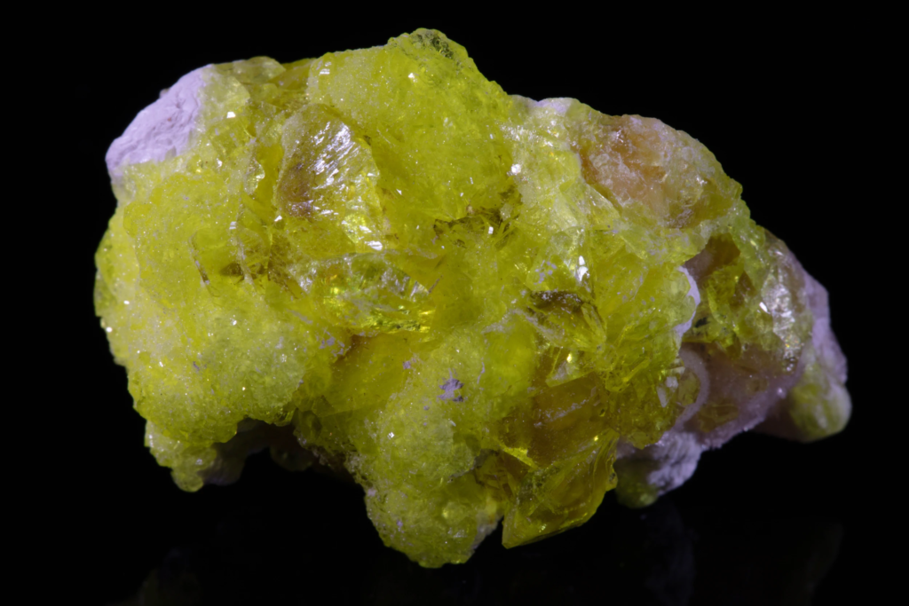 Close up macro of translucent yellow jouravskite crystals on matrix.