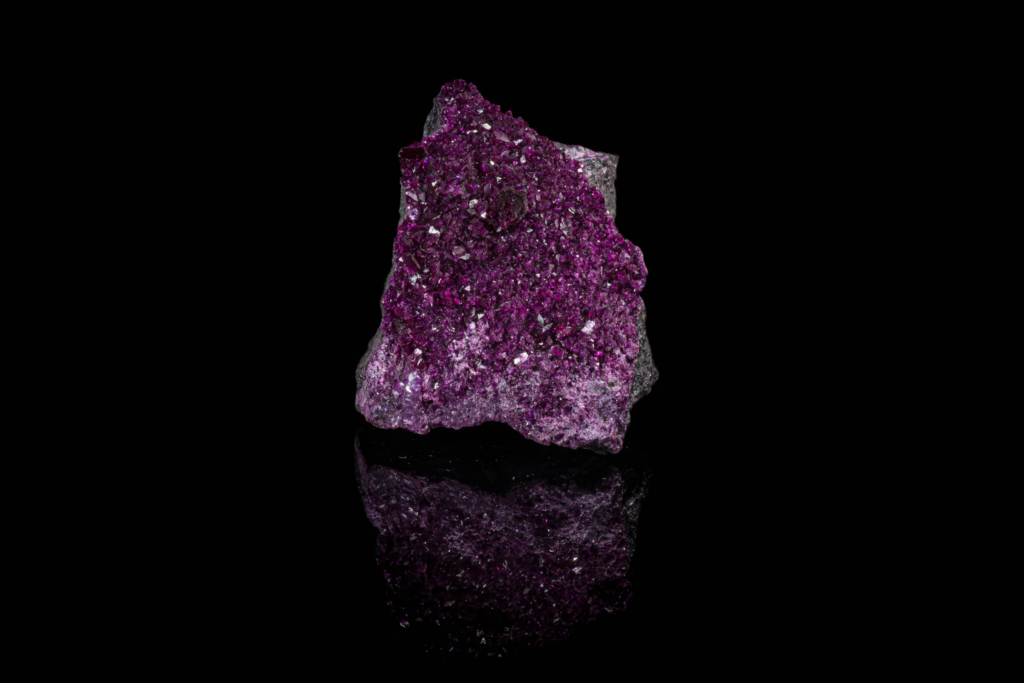 Vibrant purple kammererite crystal cluster displaying full vertical mirror reflection.