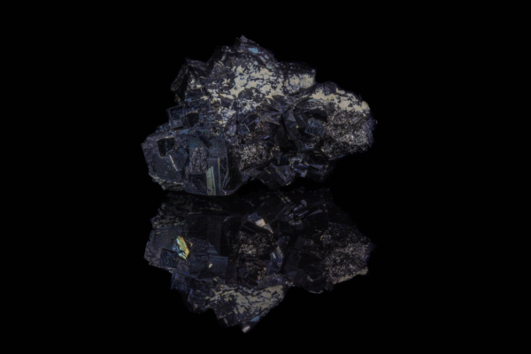 Black metallic magnetite crystal cluster displaying a vertical mirror reflection.
